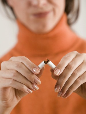 A woman breaking a cigarette in half.