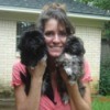 Kortney's Puppies (Shih-Tzu) - Woman holding up 2 dark haired Shih Tzu puppies.