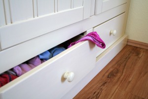 A chest of drawers with clothing in them.