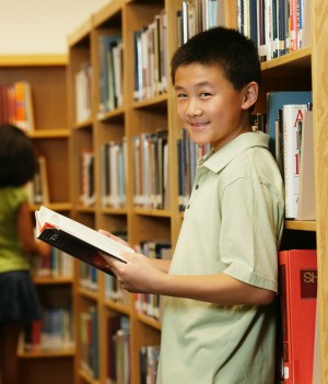 Photo of a sixth grading reading a book in a library.