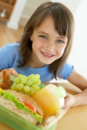 A grade school age girl eating lunch.