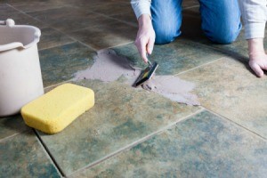 A handyman replacing floor grout.