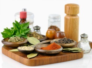 A cutting board with ground spices and fresh spices on it.