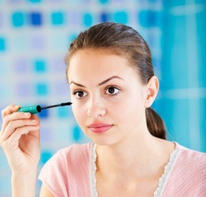 A teen girl putting on makeup.