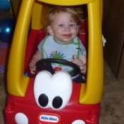 Toddler in red and yellow Little Tikes car.
