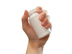 Photo of a hand holding a supplement bottle.