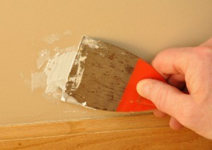 Applying putty to a damaged portion of a painted wall.