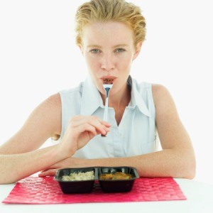 A woman eating a microwave meal.