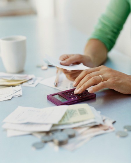 A woman using a calculator to add up expenses.