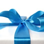 A wedding gift wrapped with white paper and a blue ribbon tied in a bow.