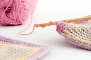 Crochet hook and pink yard.