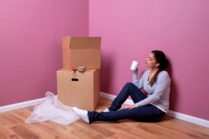 Young woman sitting next to moving boxes.