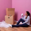 Young woman sitting next to moving boxes.