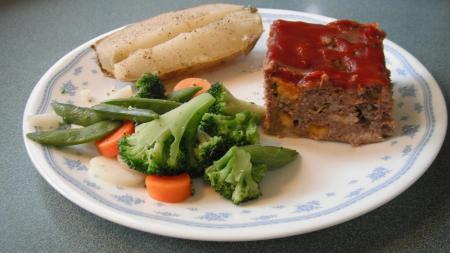Square of meatloaf with vegetables.
