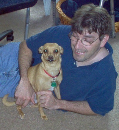 Man lying on floor next to sitting dog.