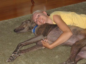 Woman laying with Greyhound.