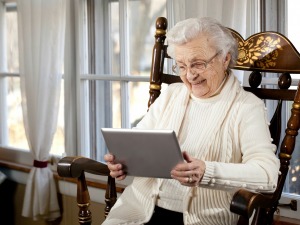 A grandma smiling while using her tablet computer.