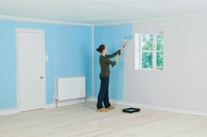 A woman painting a room blue.