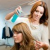 A hairdresser applying hairspray to a client in a salon.