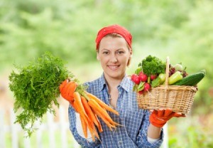 Woman holding up vegetables from her garden.