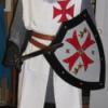 Person dressed as a knight wearing a white tunic with a red cross on the chest.