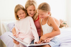 A babysitter reading to two girls.