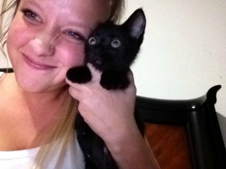 Young woman holding black kitten.