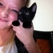 Young woman holding black kitten.