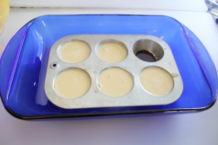 Adding custard mixture to caramel in muffin pan.