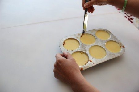 Loosening flan in muffin pan with a knife.
