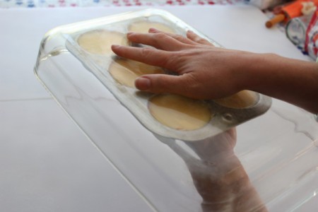 Hands gripping muffing pan inside baking dish.