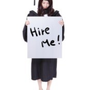 A high school graduate holding a sign that says hire me.