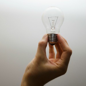 A hand holding an incandescent bulb.