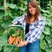 A girl holding a basket full of vegetables.