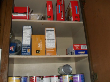 Closeup of shelves with boxes on top shelf lying on their sides.