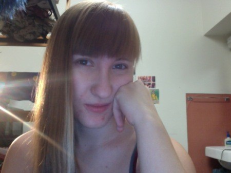 Girl with honey blond hair with bangs looking at the camera.