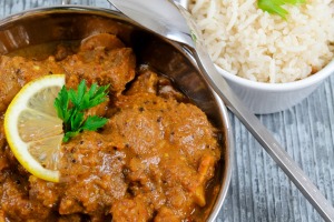 Lamb curry in a pan with a side of white rice.