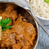 Lamb curry in a pan with a side of white rice.