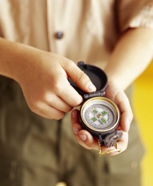 A boy scout looking at a compass.