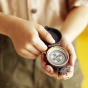 A boy scout looking at a compass.