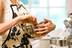 A woman wearing an apron mixing cookies.