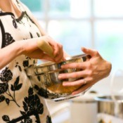 A woman wearing an apron mixing cookies.