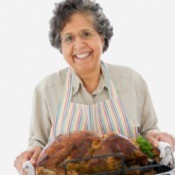 A woman holding a cooked turkey.