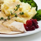 A plate of turkey dinner with turkey, cranberries and mashed potatoes.