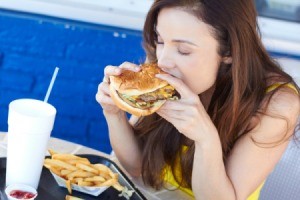 How to Get Grease Out of Fabrics - Woman eating a greasy hamburger