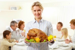 A woman holding a turkey for her family at Thanksgiving.