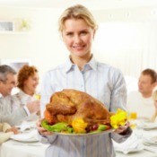 A woman holding a turkey for her family at Thanksgiving.