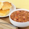 A bowl of ham and bean soup with corn bread.