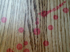 Red wax stains on wood floor.