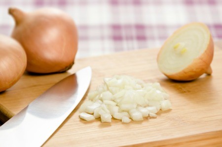 Onions being chopped on a cutting board.